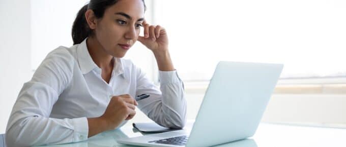 Woman Deliberating While Looking at Laptop