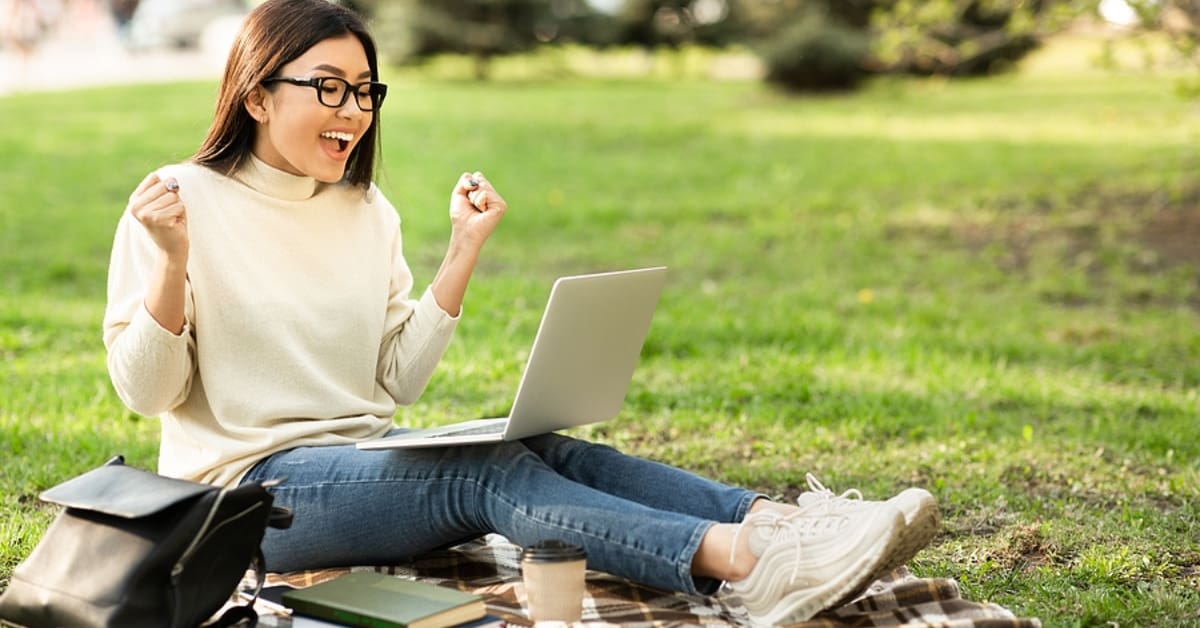 Woman Sitting Outside on Laptop Celebrating