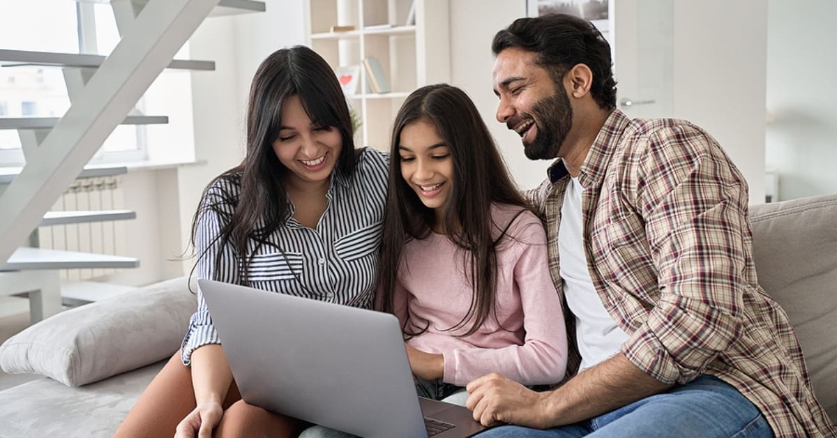 Parents and Child Smiling Looking at Laptop Together