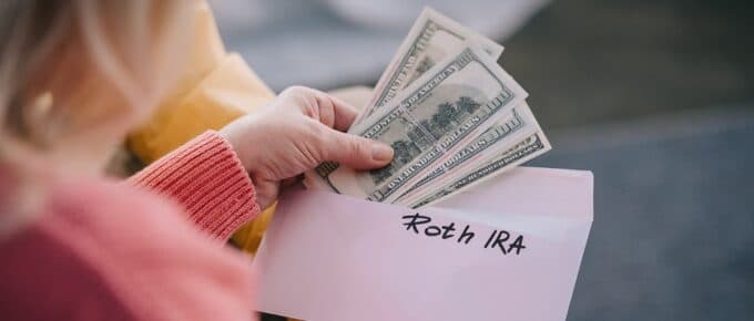 Roth IRA Labeled Envelope with Money Being Taken out of it