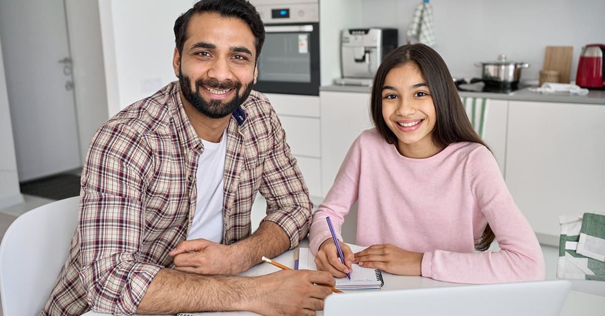 Father and Daughter Smiling for Camera While Sitting in Kitchen