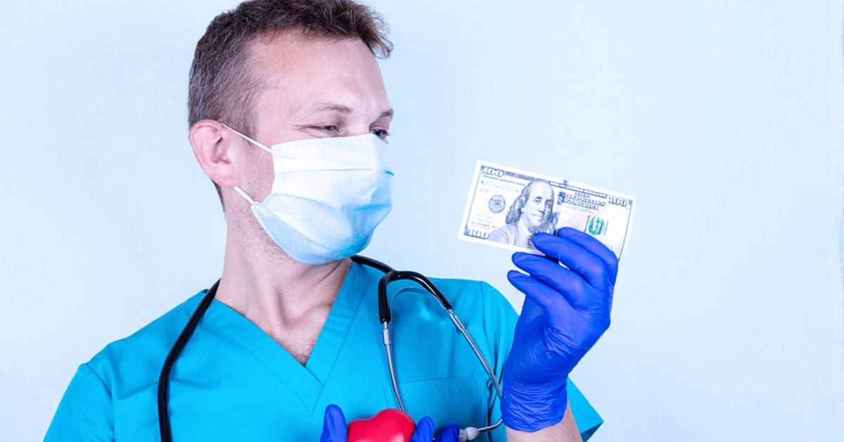 Male Medical Professional Smiling with Gloves on Holding Hundred Dollar Bill