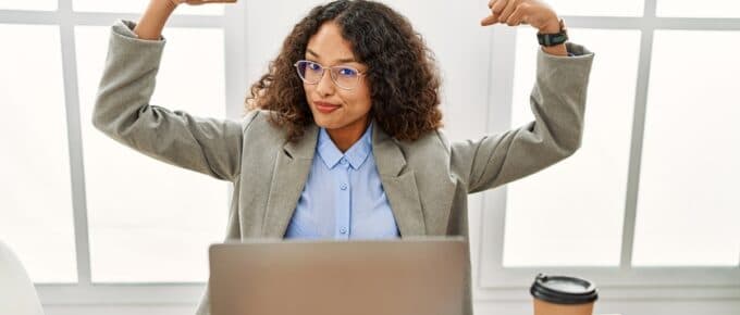 Woman Posing for Camera Making Strong Pose While Sitting in Front of Laptop