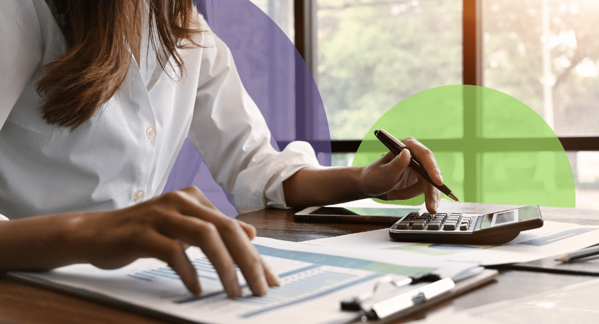 A woman from her shoulders down working on a calculator and piece of paper