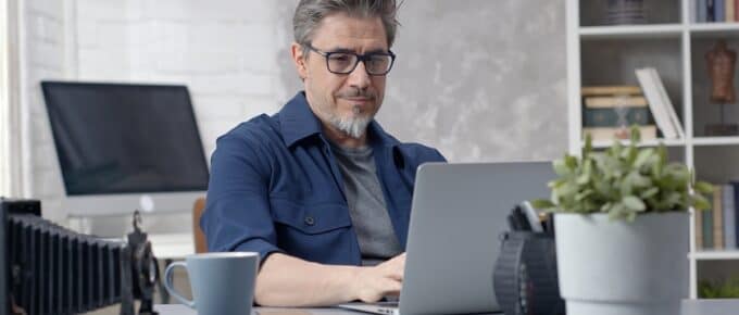Man Posing in Front of Laptop Sitting at Desk