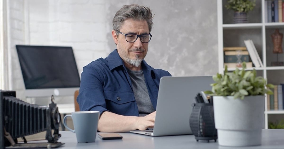 Man Posing in Front of Laptop Sitting at Desk
