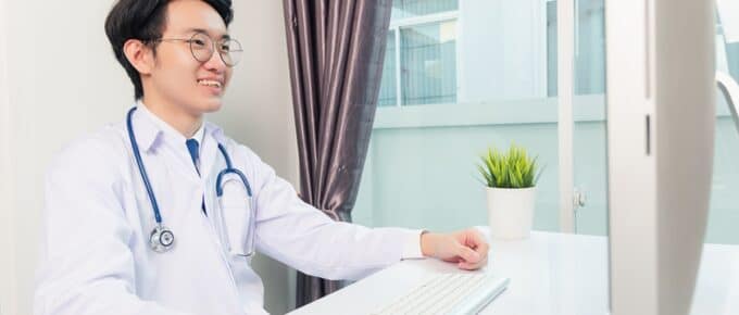 Asian Male Physician Smiling at his Computer Monitor