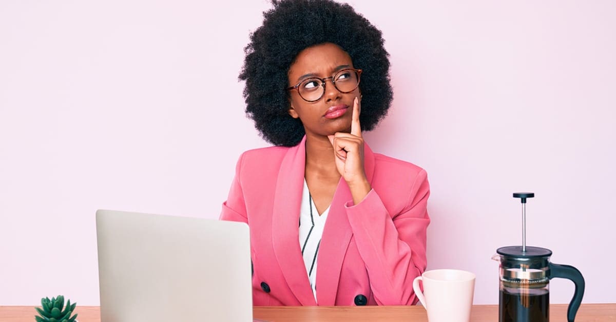 African American Woman Posing in Pondering Stance in Front of her Laptop