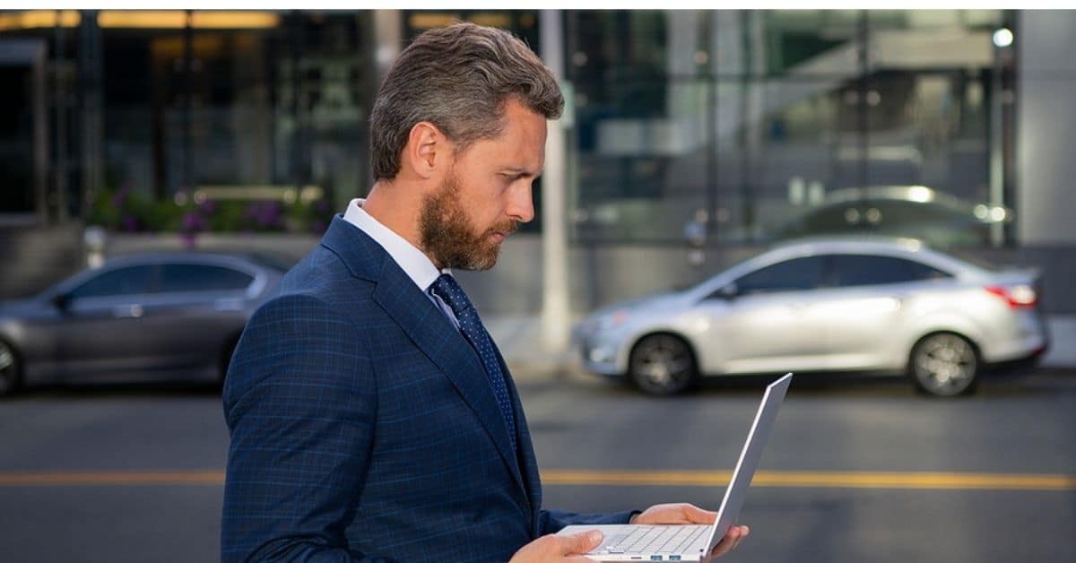 Man Concentrating Looking at Laptop While Standing Outside