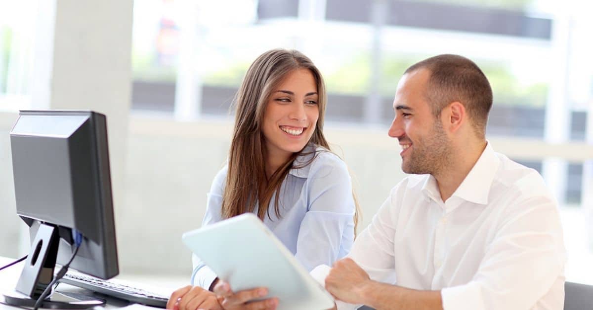 White Male and Female Smiling at Each other While Sitting in Front of a Camera