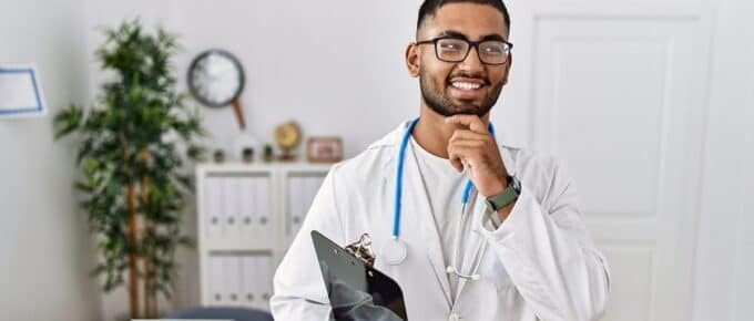 Black Male Doctor Smiling Posing for Camera with Clipboard in Hand