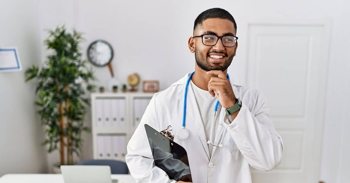 Black Male Doctor Smiling Posing for Camera with Clipboard in Hand