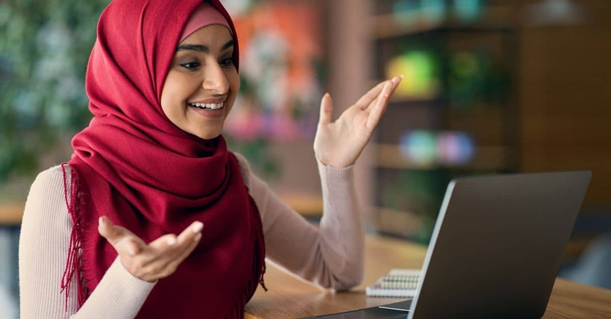 Muslim Woman Smiling While Looking at Laptop