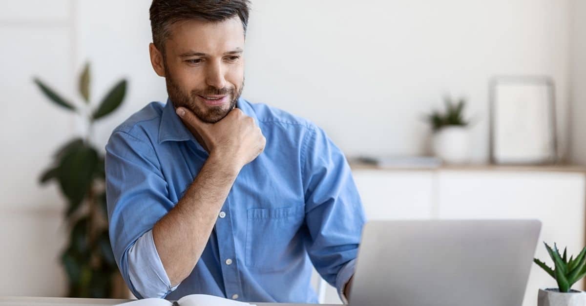 White Man with Beard Grinning Looking at Computer