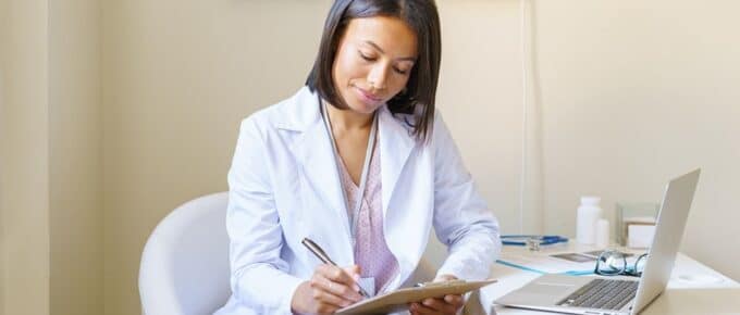 African American in White Coat Taking Notes