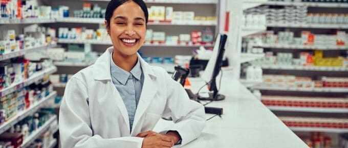 pharmacists standing at counter with medicine on shelves in the background