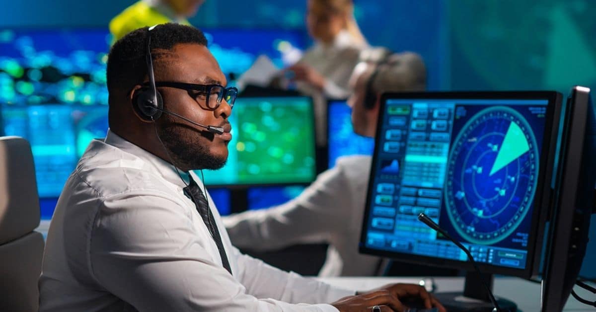 African American Man with Headset Tracking a Map on a Computer