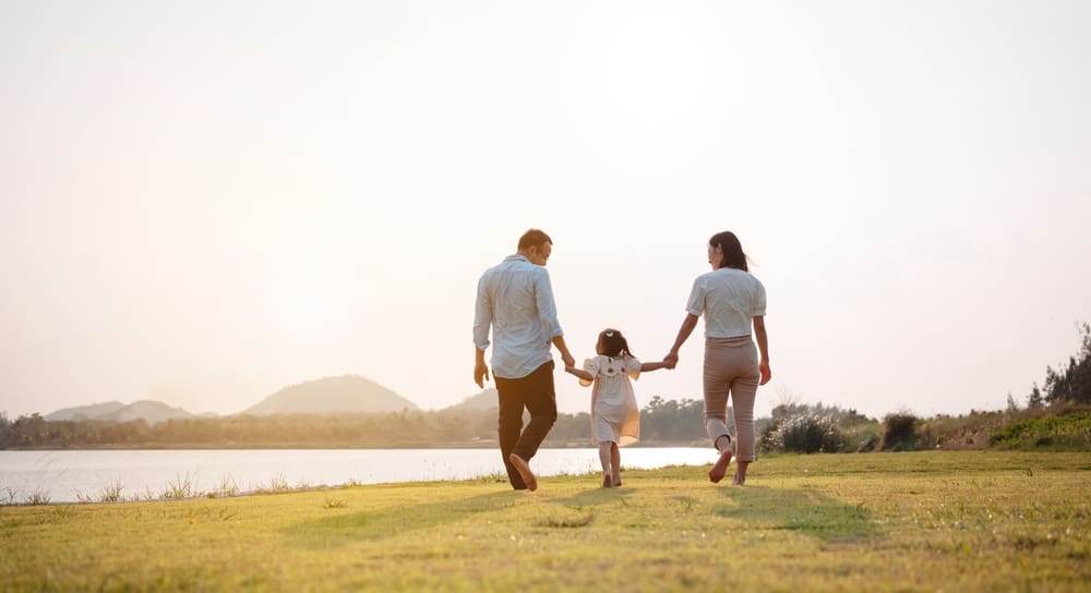 Family walking outside away from the camera and holding hands.