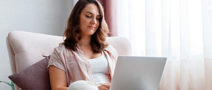 dark haired woman sitting on couch with laptop