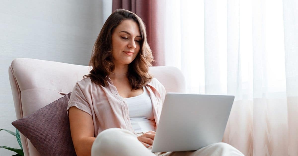 dark haired woman sitting on couch with laptop