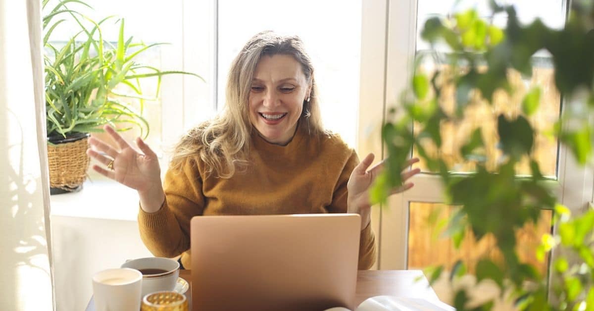 happy middle aged woman sitting down with a laptop