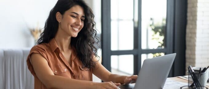 Young smiling Caucasian woman working on laptop from home