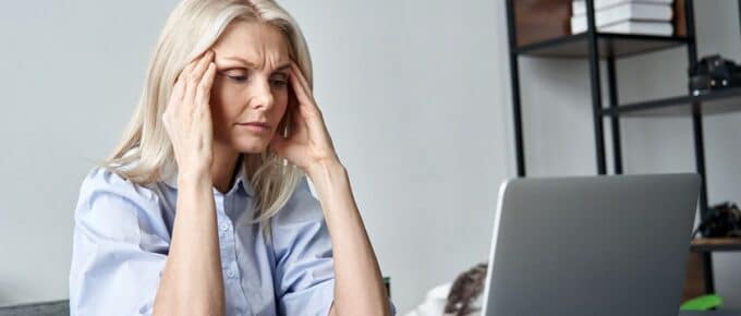 female woman holding head looking at computer
