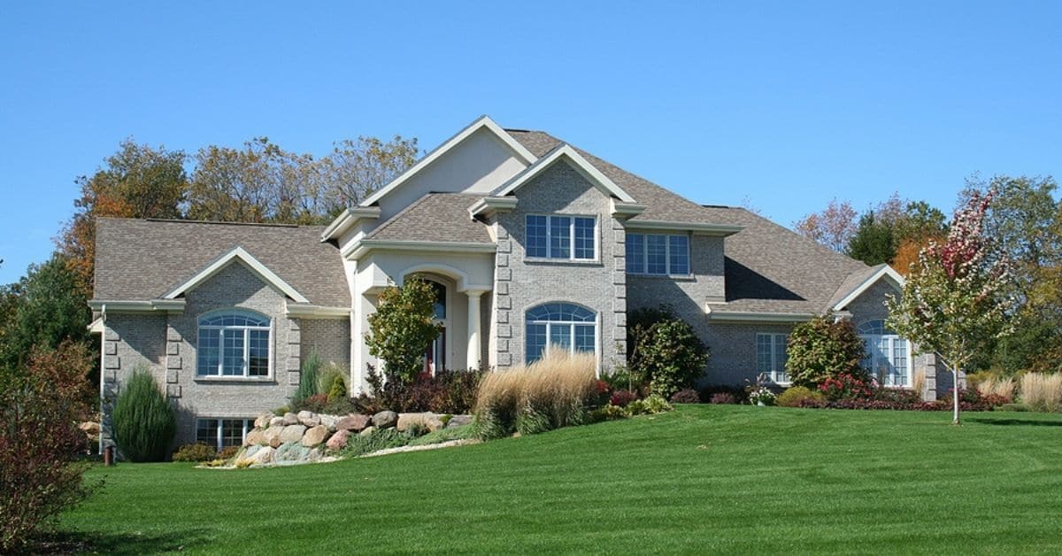 luxurious brick executive house with blue sky and green grass