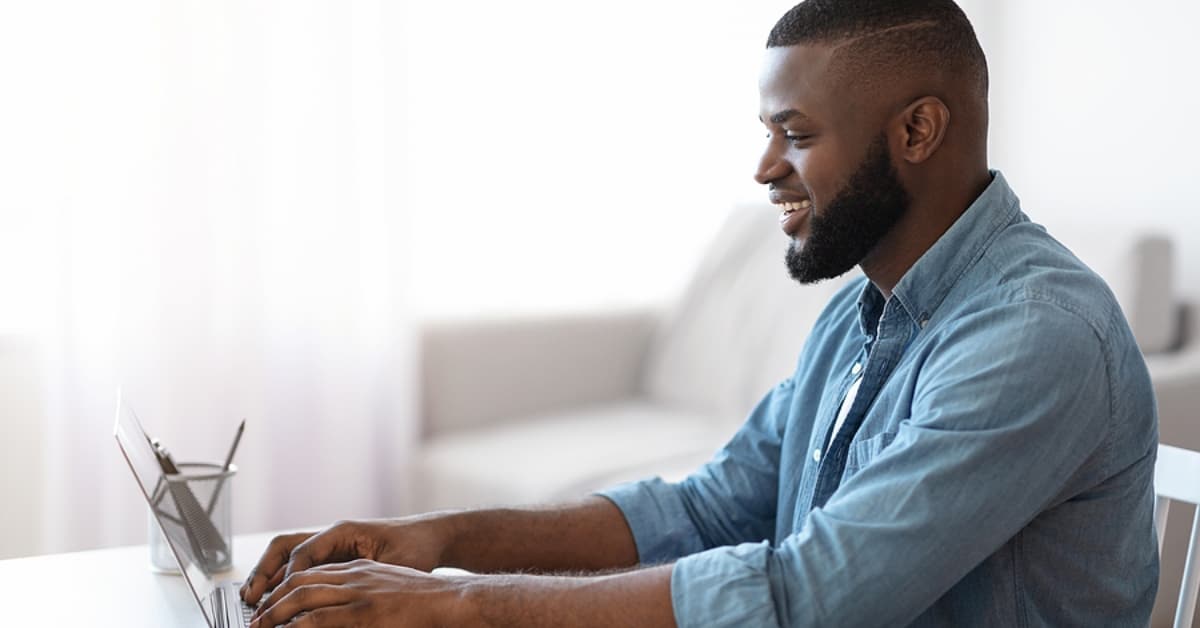 Smiling Millennial African American Man Working With Laptop