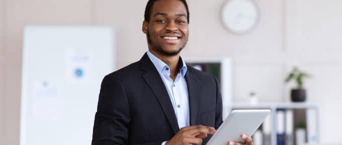 Smiling black entrepreneur young man holding digital tablet