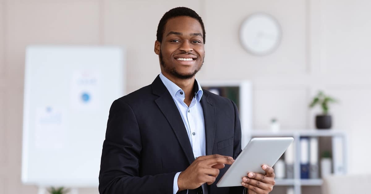 Smiling black entrepreneur young man holding digital tablet