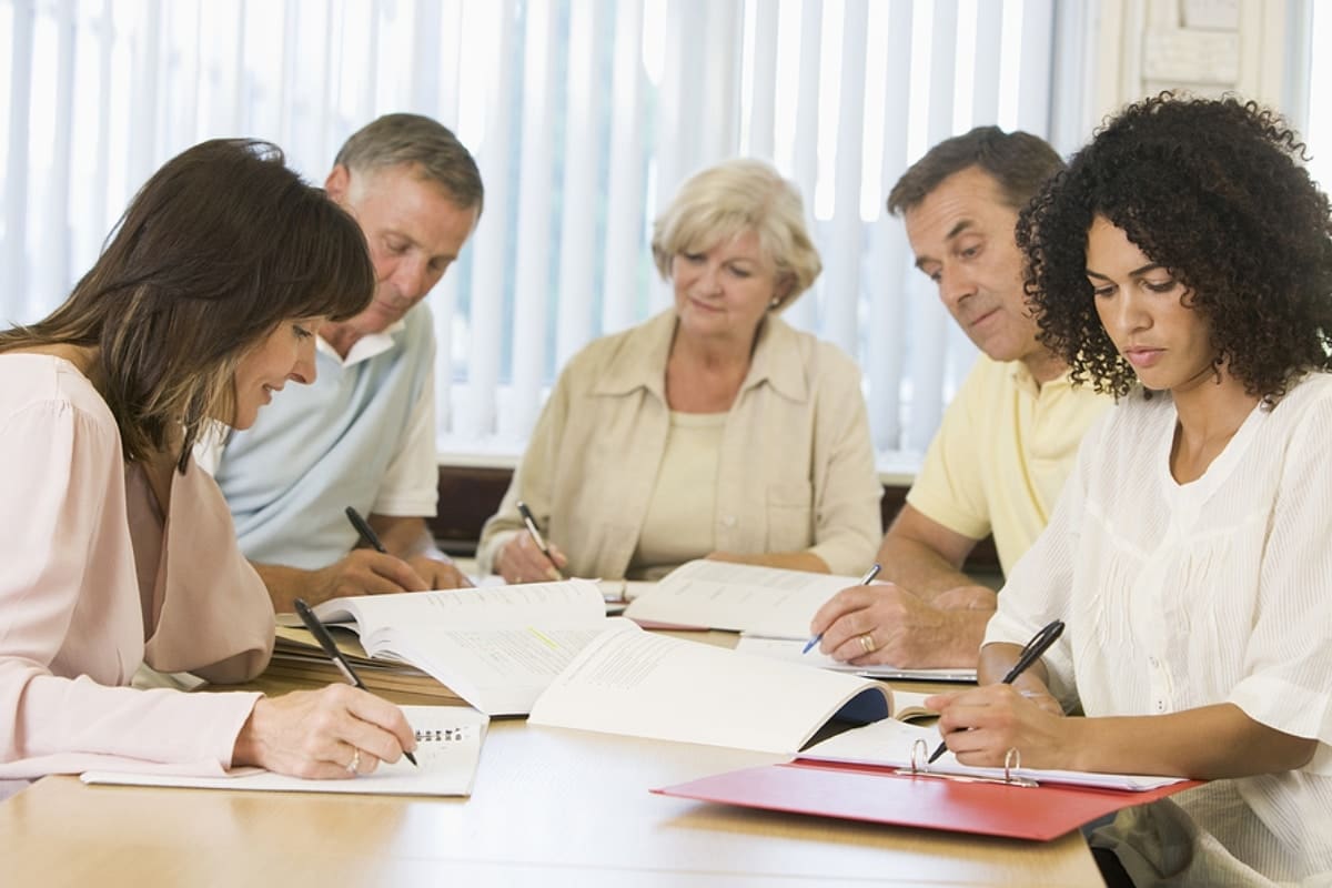 Five adult students studying at table