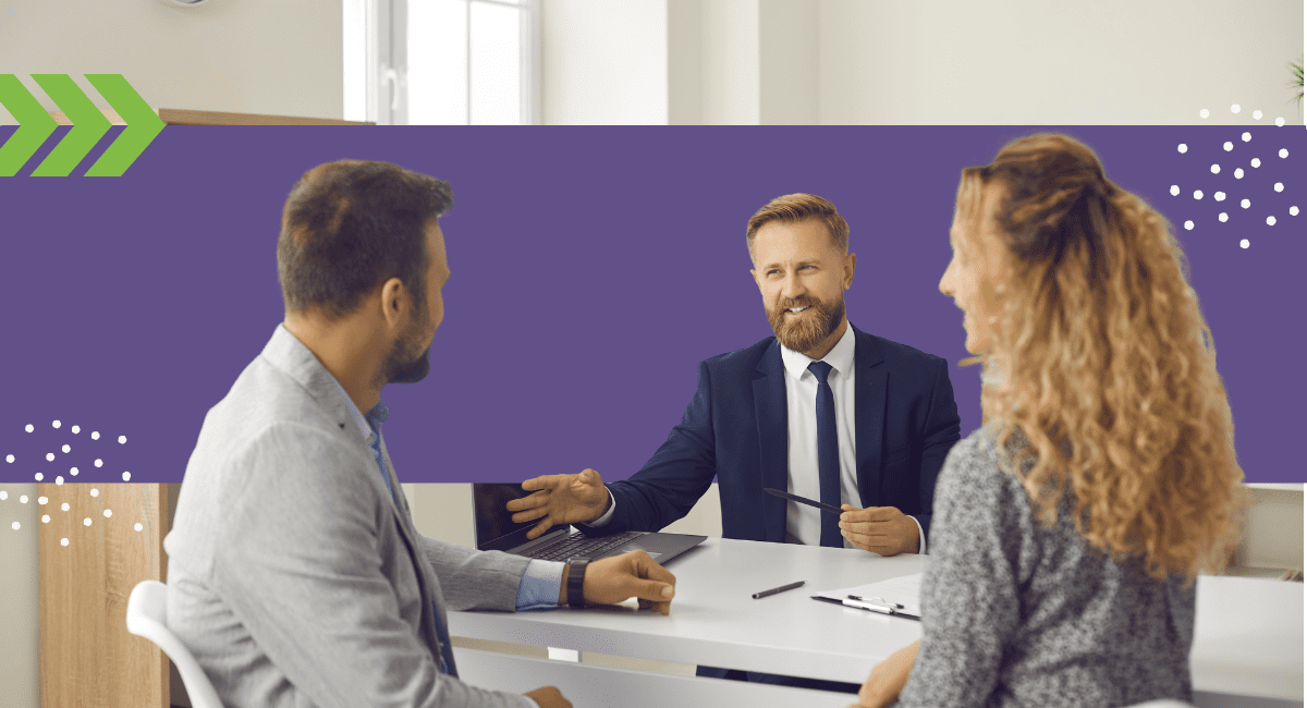 A man in a business suit talking to a young couple at his office