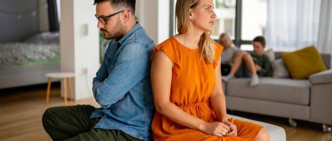 frustrated couple sitting back to back with arms crossed, clearly unhappy