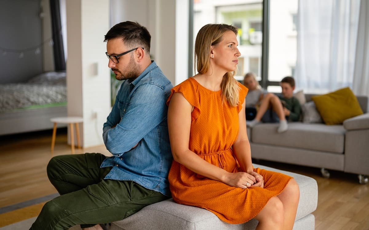 frustrated couple sitting back to back with arms crossed, clearly unhappy