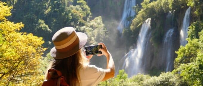 Back view of travel blogger woman on trip or adventure on Tee Lor Su waterfall in Thailand.
