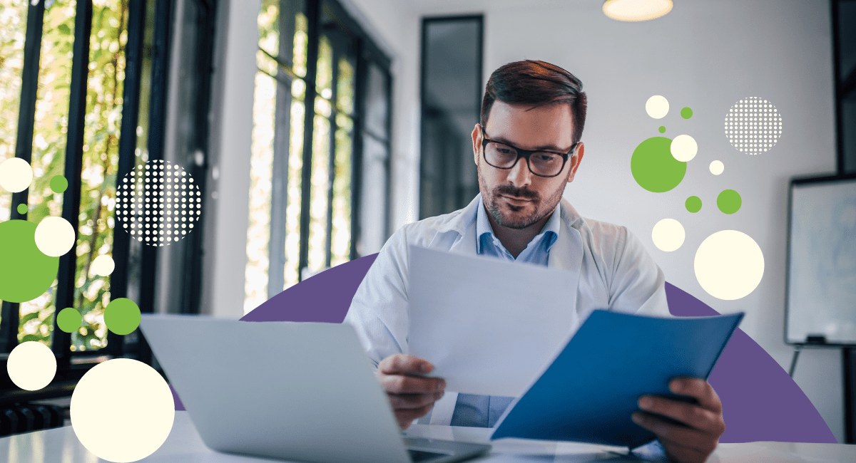 male physician looking at papers, laptop in front of him