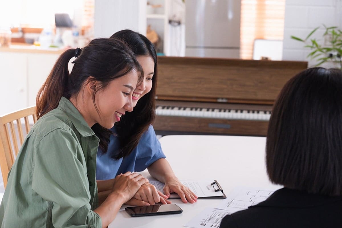 Happy asian couple sign contract for buy new house with realtor agent