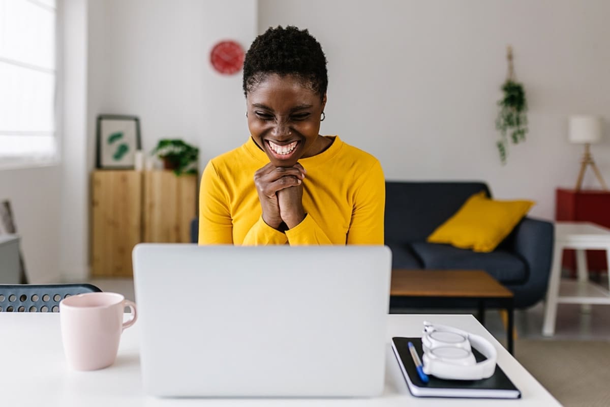 Excited young african woman celebrating success looking at laptop screen