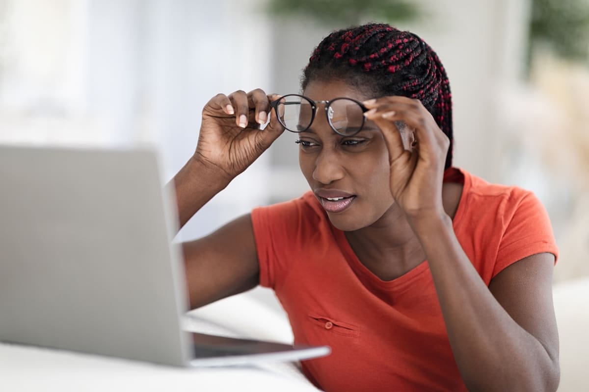 Confused Black Woman Taking Off Eyeglasses And Looking At Laptop Screen