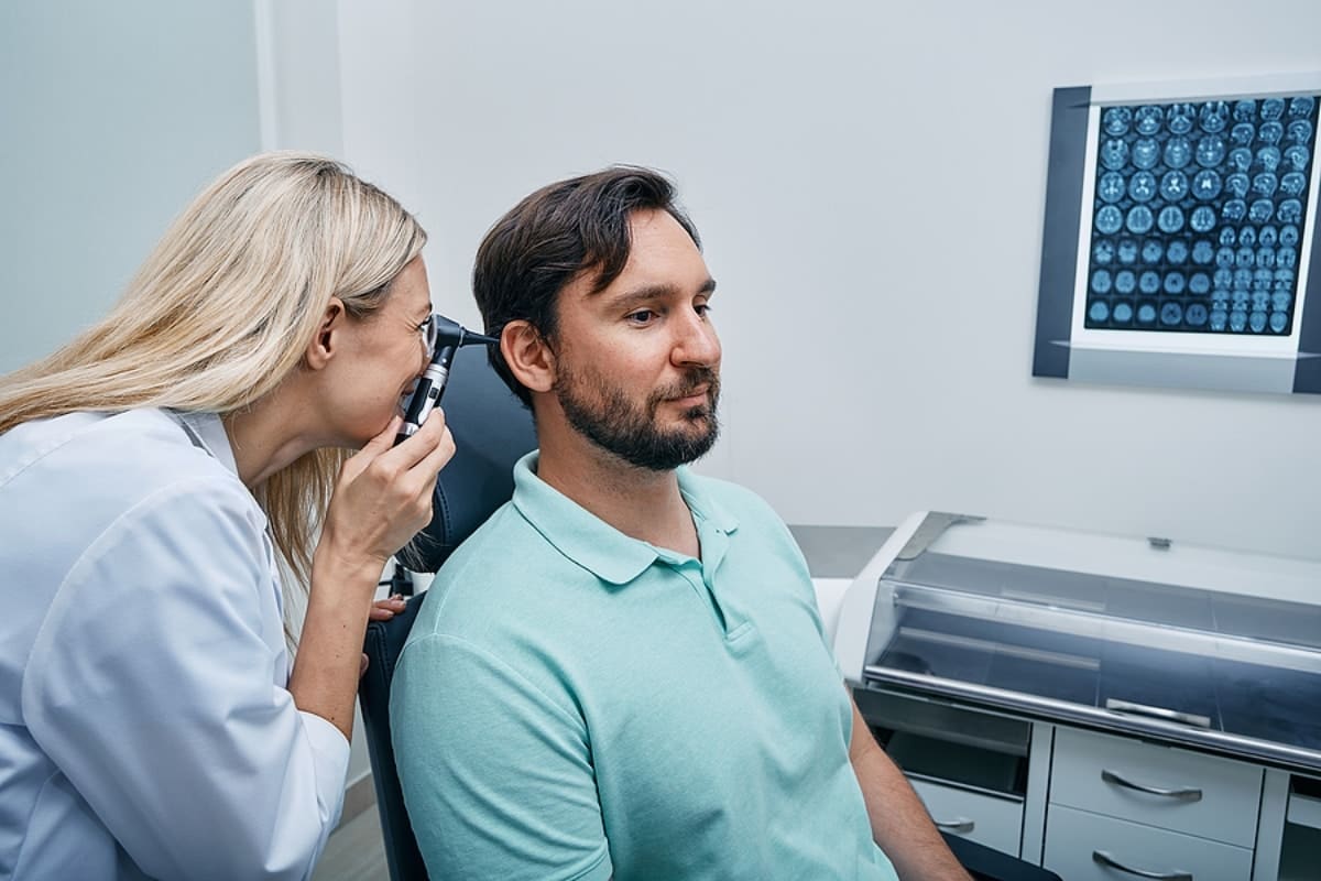 Otolaryngologist doctor checking mans ear using otoscope or auriscope at medical center