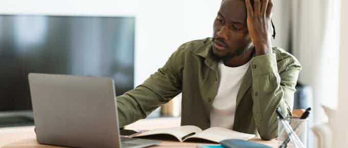 Thoughtful black man using laptop computer