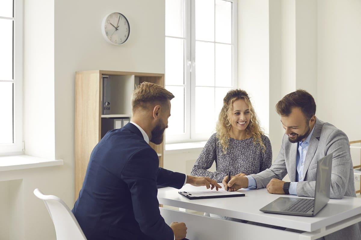 Man and woman sit at a table with a financial planner to discuss student loan repayment strategies.