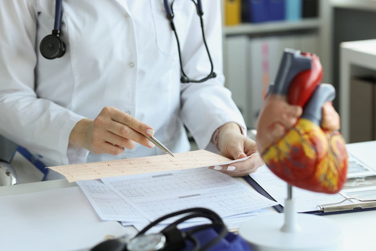 Cardiologist doctor holding and reading an ecg paper report of patient with heart disease.