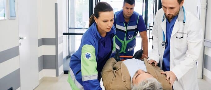 Paramedics and doctor rushing with victim patient on ambulance stretcher on hospital corridor at emergency department.