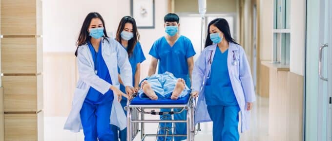 Group of professional medical doctor team and assistant with stethoscope in uniform taking seriously injured coma patient to operation emergency theatre room in hospital