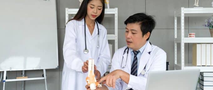 Young asian Orthopedic Surgeons in white gown and stethoscope asking for the professor advice about bone, joint, tendon and muscle.