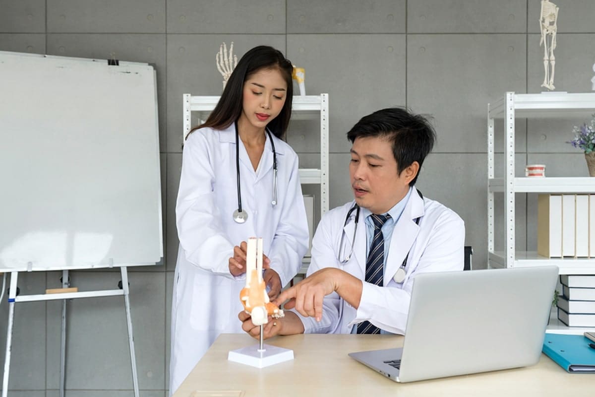 Young asian Orthopedic Surgeons in white gown and stethoscope asking for the professor advice about bone, joint, tendon and muscle.