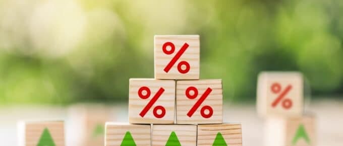 Wooden cube block with interest rate and up arrow.