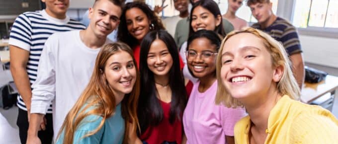 United multiracial big group of student friends taking selfie with teacher at college